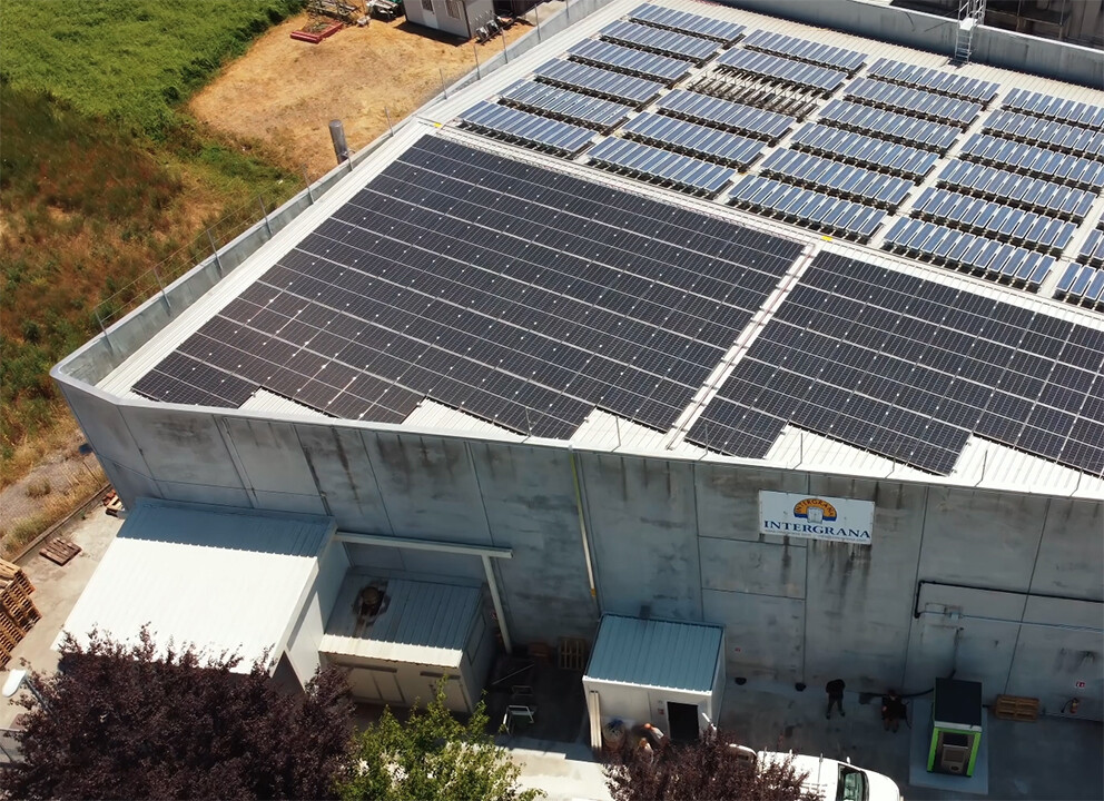 Vista aerea di un'azienda con pannelli fotovoltaici sul tetto e un'insegna con scritto Intergrana
